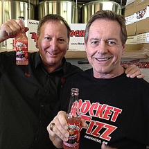 Wrestling legend and actor Rowdy Roddy Piper and Rocket Fizz co-founder Rob. They are holding Roddy&#039;s famous Bubble Gum Soda Pop. Rocket Fizz bottles and distributes this awesome soda pop which is based on the movie They Live.