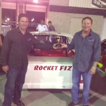 Rocket Fizz co-founders Rob and Ryan standing with the Rocket Fizz NASCAR race car.